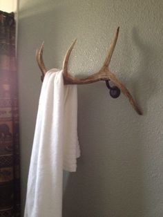 a deer antler mounted to the side of a wall next to a towel rack