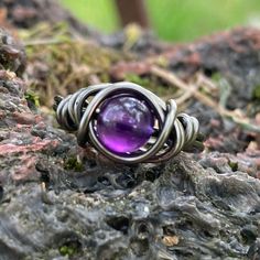 Amethyst ring made with non tarnish grey plated wire and a 6mm amethyst crystal that has been ethically sourced from a reputable supplier. Custom made to fit any USA size 4-14 including half and quarter sizes! Comes in a gift box. Amethyst is a purple stone, known as a "Gem of Fire" by ancient cultures. It was greatly sought after throughout history and at times valued as highly as Diamonds. Today, this semi-precious variety of quartz is found in many locations around the world. The presence of Manganese in the stone produces the purple hue, and variation of the amount of iron in the stone creates a color range from reddish purple to deep violet to light lilac. The name derives from the Greek word for "not intoxicated" and was once believed to prevent drunkenness and overindulgence.  Ameth Nickel-free Purple Amethyst Ring, Adjustable Purple Amethyst Ring, Adjustable Purple Crystal Ring For Healing, Adjustable Spiritual Purple Amethyst Ring, Spiritual Adjustable Amethyst Ring, Adjustable Spiritual Purple Ring, Unique Adjustable Purple Crystal Ring, Adjustable Purple Crystal Birthstone Ring, Adjustable Spiritual Amethyst Ring