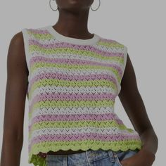 a woman is wearing a crocheted top and denim shorts with her hands in her pockets