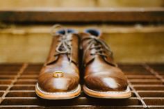 a pair of brown shoes sitting on top of a metal grate