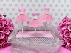 two pink cake pops sitting on top of a table next to purple flowers and paper fans