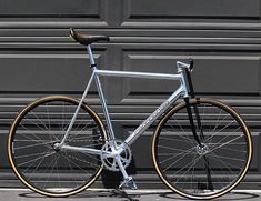 a silver bicycle parked in front of a garage door with no wheels on it's rims