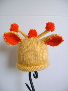 a knitted hat with ears and orange pom - poms hanging on a hook