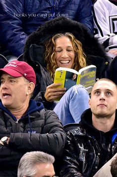 people sitting in the stands at a sporting event and one person is reading a book