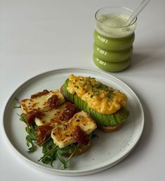 a white plate topped with food next to a green drink