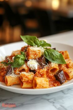 a white plate topped with pasta covered in sauce and cheese on top of a marble counter