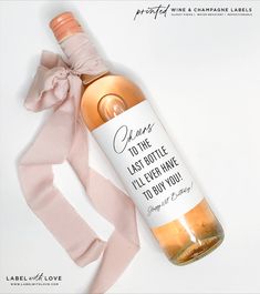 a bottle of wine sitting on top of a white table next to a pink ribbon