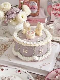 there is a cake with two teddy bears on it and flowers in the vases