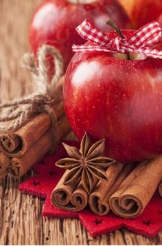 an apple, cinnamon sticks and star anise on a wooden table with red napkins