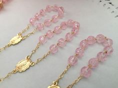 "20 Rosarios pequeñitos o decenario en color rosa., hechos a Mano con la Imagen de la virgen de Guadalupe , bañados en Oro y hechos de acrilico con figurita de rosa. Mide cerca de 10cm de largo y Las cuentitas importados son de 6 mm. 20 PINK COLOR , ACRYLIC BEADS IN SHAPE OF ROSEBUDS ON THIS MINI ROSARIES . ALL HAND MADE AND GOLD PLATED THEY MEASURE ABOUT 4\" INCHES EACH. COMVO US WITH Any QUESTIONS. Thanks!" Personalized Pink Rosary Bracelet For Baptism, Pink Beaded Jewelry For Baptism, Pink Beaded Jewelry For First Communion, Adjustable Rose Gold Rosary As Gift, Pink Rosary For First Communion, Pink Rosary With Round Beads For First Communion, Handmade Pink Rosary With Round Beads, Handmade Pink Rosary For Baptism, Handmade Pink Rosary For First Communion