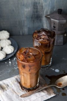 two glasses filled with iced coffee sitting on top of a table