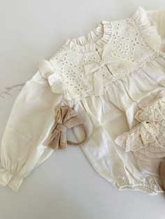 Indulge in luxury with our Arabella Embroidered Romper. The long sleeve design, delicate embroidered details, and charming bow applique exude elegance and sophistication. Made from soft cotton, this romper will provide comfort and style for your little one. The perfect addition to a fashionable wardrobe. Chic Long Sleeve Sets With Floral Embroidery, Long Sleeve Dress With Bow For Baptism, Cream Long Sleeve Baptism Set, Cream Cotton Sets For Baptism, Elegant Long Sleeve Sets With Ruffles, Elegant Long Sleeve Ruffled Set, Beige Long Sleeve Set With Floral Embroidery, Cute Cotton Sets With Bow Detail, Cute Cotton Sets With Bow