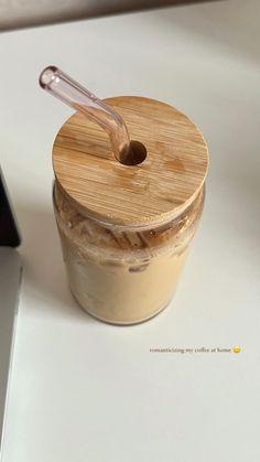 a glass jar with a spoon in it sitting next to a laptop