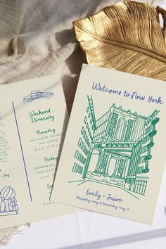 the welcome to new york cards are next to a gold leaf on a white tablecloth