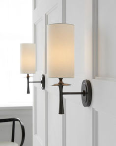 two lamps on the wall next to each other in a room with white walls and chairs