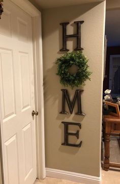 there is a sign that says home with a wreath hanging on the wall next to it