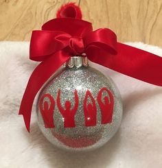 a silver ornament with red hand prints on it and a red ribbon around the top