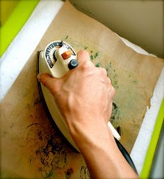 a person is using an iron on top of a piece of paper with a marker