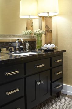 a bathroom vanity with two lamps on top of it