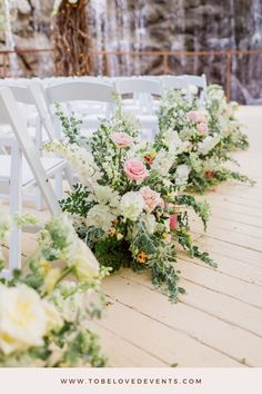 the aisle is lined with white chairs and flowers