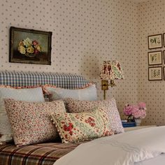 a bed with many pillows on top of it and a painting above the headboard