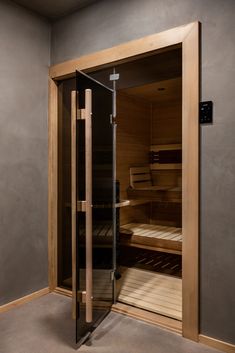 an empty sauna in the corner of a room with glass doors and shelves on both sides