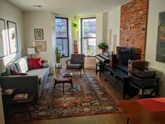 a living room filled with furniture and a brick wall in the background on top of a wooden floor