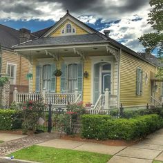 a yellow house with white trim on the front porch and stairs to the second floor