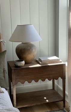 a wooden table with a lamp on top of it next to a book and other items