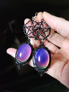 Our latest design is inspired by moody witches.  We've taken black pentacle charms and posited them up with gorgeous color changing mood cabochons made of glass set in an ornate black frame.  Perfect witchy goth earrings! 🥰  - Glass 25x18mm mood color changing with heat cabochons - black pewter pentacle and materials - Stainless steel earrings hooks with rubber backs included. Handmade Black Fantasy Earrings, Mystical Nickel-free Black Jewelry, Mystical Black Nickel-free Jewelry, Black Fantasy Style Pierced Earrings, Black Fantasy Earrings, Black Fantasy Style Earrings, Black Nickel-free Mystical Jewelry, Mystical Black Metal Earrings, Mystical Black Metal Jewelry