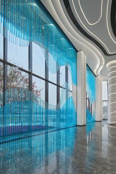 an empty lobby with large windows and blue curtains