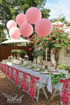 a table set up for a party with pink balloons