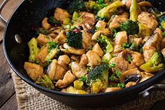 chicken and broccoli stir fry in a skillet on top of a wooden table