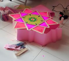 a pink box sitting on top of a white tiled floor next to other craft supplies