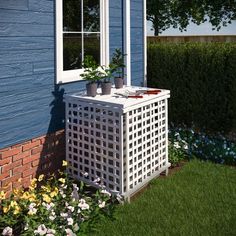 a white planter sitting in front of a blue house with flowers growing out of it