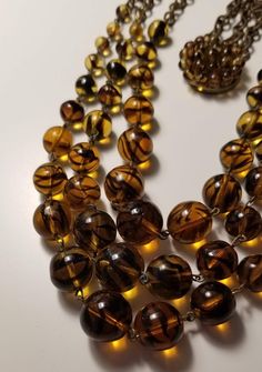 Vintage 1950s beaded necklace consisting of a three strands of amber color beads with stripes, likely made of colored Lucite. The elegant costume piece is held together by a beaded box clasp. Shortest of the three strands is 18" and the longest is about 21 1/2".  Keep shopping my store here: https://www.etsy.com/shop/OldGoodFinds Color Beads, Natural Amber, Box Clasp, Amber Color, Necklace Vintage, Vintage 1950s, Vintage Necklace, Amber, Beaded Necklace