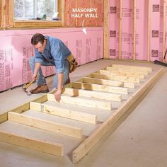 a man working on the floor in a room under construction with pink walls and wooden beams