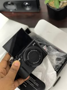 a person holding a camera in their hand near a box with the lens on it