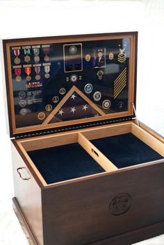 an open wooden box with medals and other items in it's display case on a white surface