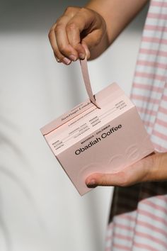 a person holding a pink box with a pair of scissors in it's hand