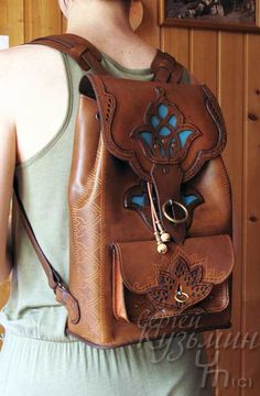 a woman wearing a brown leather backpack with an intricate design on the front and side