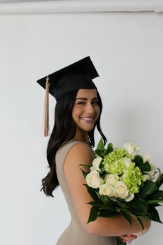 a woman wearing a graduation cap and gown holding a bouquet of flowers