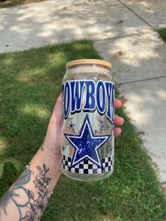 a person holding a jar with the word cowboys painted on it