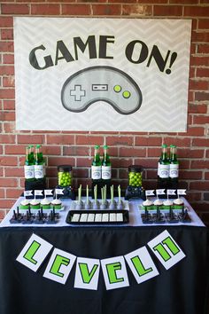 a video game themed birthday party with games on sign and dessert bar set up in front of a brick wall