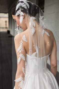 a woman in a wedding dress with white flowers on her veil and hair combs