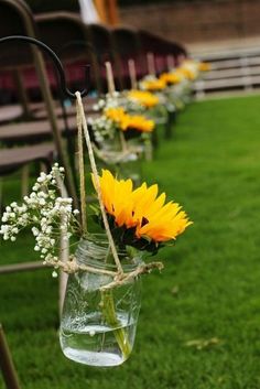 sunflowers and baby's breath are tied to mason jars in the grass