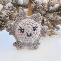 a small crocheted animal sitting on top of a white table next to a tree