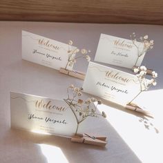 three place cards with flowers on them are sitting on a table in the sun light