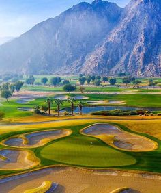 an aerial view of a golf course with mountains in the background