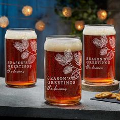 two beer glasses sitting on top of a table next to pretzels and crackers